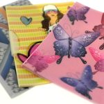 Three colorful plastic folders, manufactured in China, feature different designs: geometric shapes, a girl with a heart, and pink and purple butterflies. Perfect for organizing documents in style.