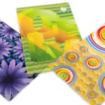 Three rectangular cards with colorful patternsโpurple flowers, abstract yellow and green shapes, and multicolored concentric circlesโare displayed on a white background, showcasing the artistry of manufacturing stationery items in China.