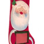 A red Christmas stocking shaped like Santa Claus holding a green-edged rectangular frame, with a holly decoration on his hat.