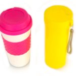 A white travel mug with a pink lid and grip next to a tall, yellow cylindrical container with a side strap, both against a white background.