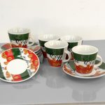 Six coffee cups with matching saucers, decorated with coffee beans and the word "coffee" in a colorful design, arranged on a gray surface against a plain background.
