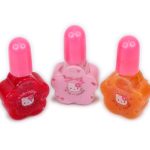 Three Hello Kitty-themed nail polish bottles in red, pink, and orange with flower-shaped bases and pink caps are arranged in a row on a white background.
