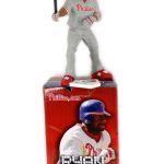 A baseball action figure in a Phillies uniform stands on a box labeled "Ryan Howard Action Figure," featuring an image of a player at bat.