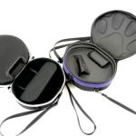 Two circular black carrying cases with shoulder straps are open to reveal padded compartments; one case has a paw print design on the inside lid.