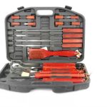 A black plastic case containing a set of barbecue tools with wooden handles, including a spatula, fork, tongs, skewers, and a grill brush.
