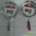 Two metal grill pans with perforated surfaces and round shapes are placed side by side on a tiled floor; one has a plastic-wrapped handle, the other has a wooden handle.