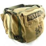 A tan canvas bag with green straps, featuring "MEMOIR '44" text and an illustration of soldiers printed on the front.