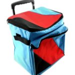 A fabric rolling cooler bag with a telescopic handle, blue, red, and black geometric design, and a front zippered pocket.