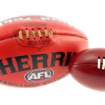Sports Equipment A large official AFL Sherrin football and a smaller toy football are displayed side by side against a white background.
