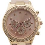 A gold wristwatch with a pink face, three small dials, crystal hour markers, and a pink leather strap. The bezel is encrusted with crystals.