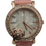 A round wristwatch with a pink leather strap, a jeweled bezel, a floral decoration, and a mother-of-pearl dial with gold hour markers and hands.
