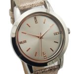 A wristwatch with a metallic round face, rose gold hour markers with small crystals, and a textured light pink strap.