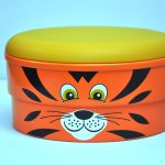 An orange round container with a yellow lid, featuring a cartoon tiger face on the side.